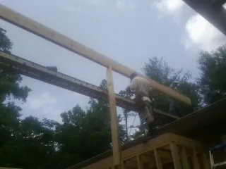 Carpenter setting a ridge beam over a new addition frame — Ice Dam Removal by Roofing Brothers in Collbran