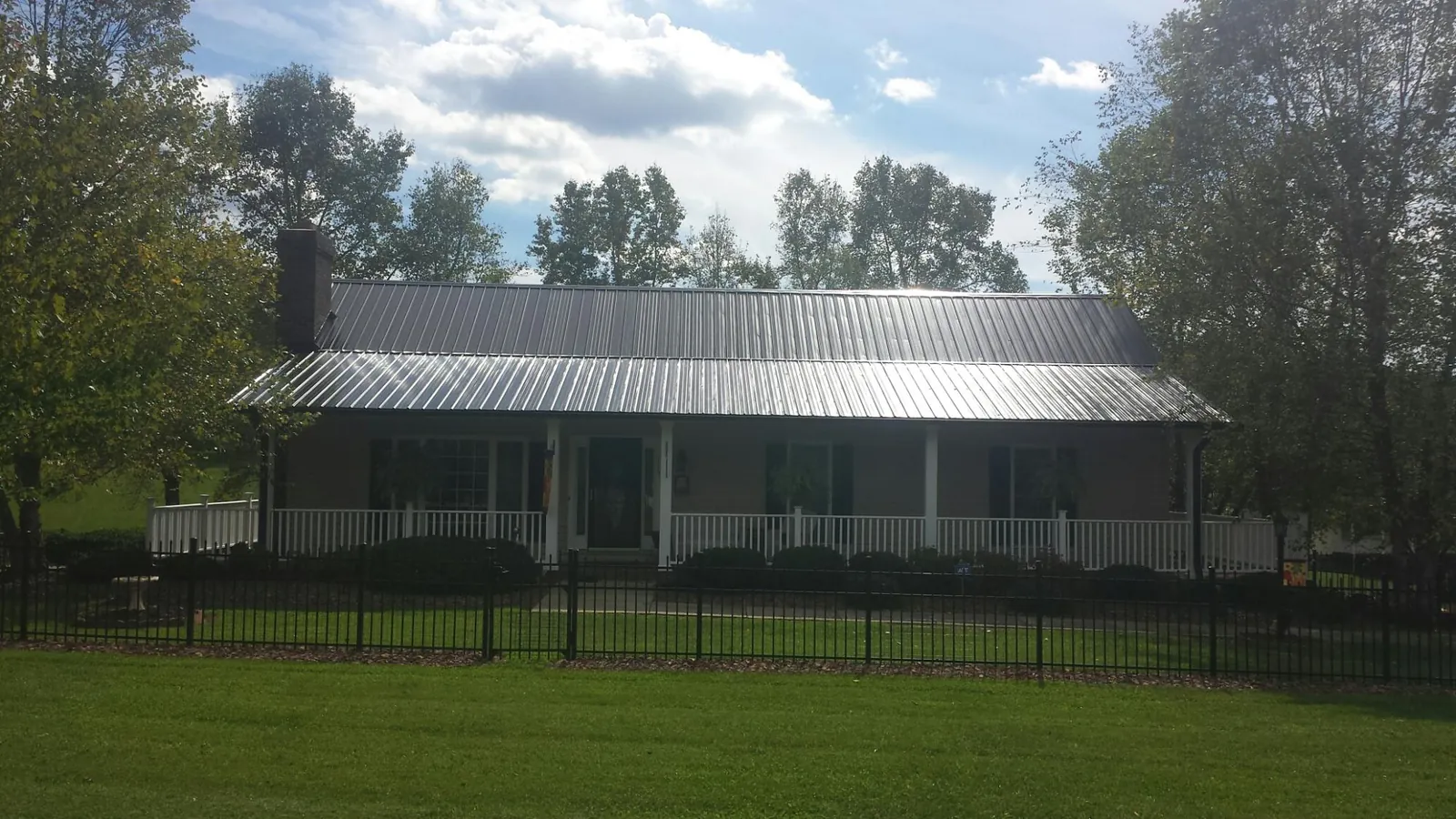Gray metal roof on a brick ranch with a full width front porch — Gutter Guard Installation work by our crew in Collbran